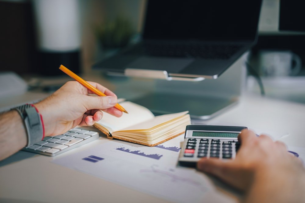 A calculator and notebook on a desk